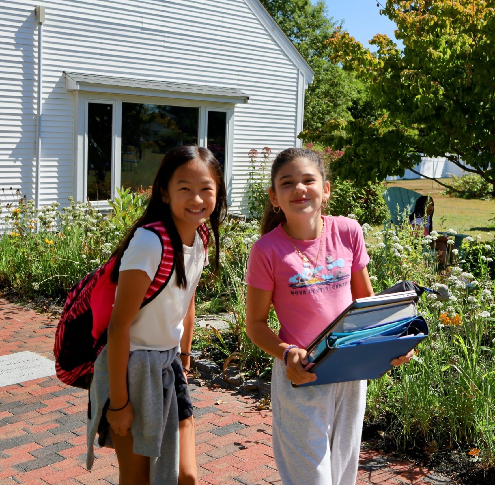 Two sixth grade girls pause and smile for the camera while crossing Votey Way on their way to class.